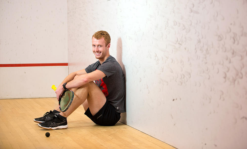 Andrew Schnell sitting down in a squash court