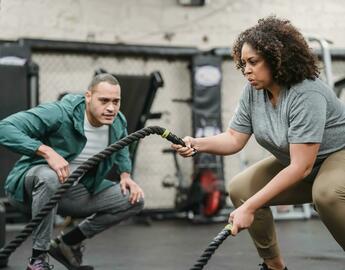 A women is doing a workout, while a coach encourages beside her